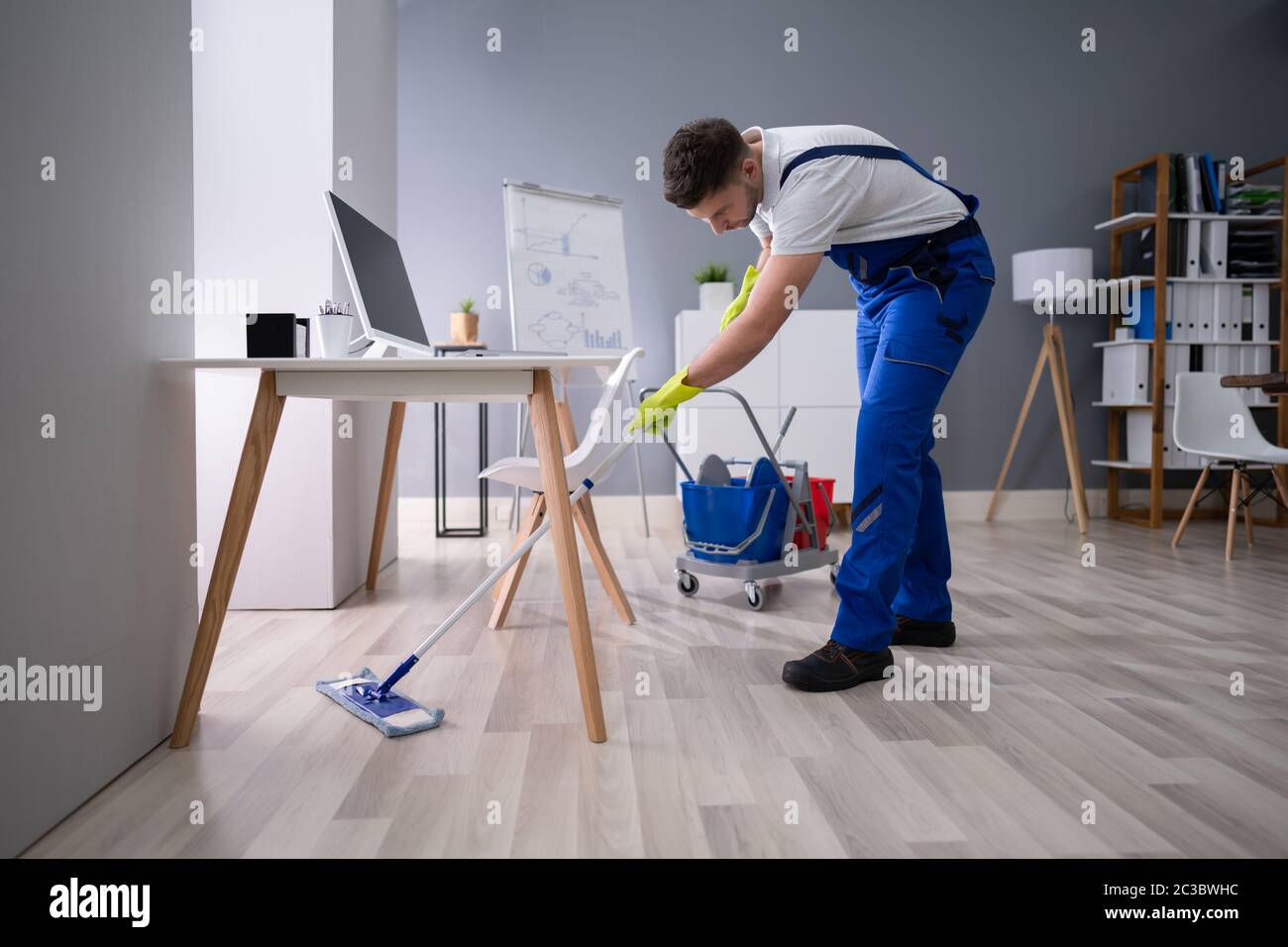 Felice Giovane la pulizia del pavimento con Mop in ufficio moderno Foto Stock