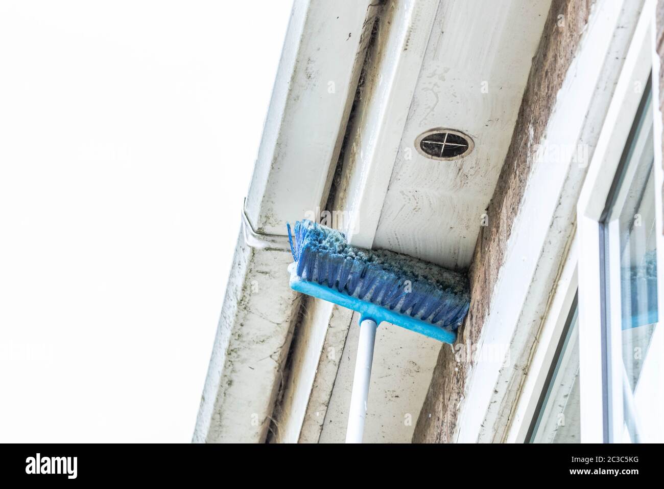 Spazzolare le ciottelle e rimuovere la polvere dalle grondaie. Foto Stock