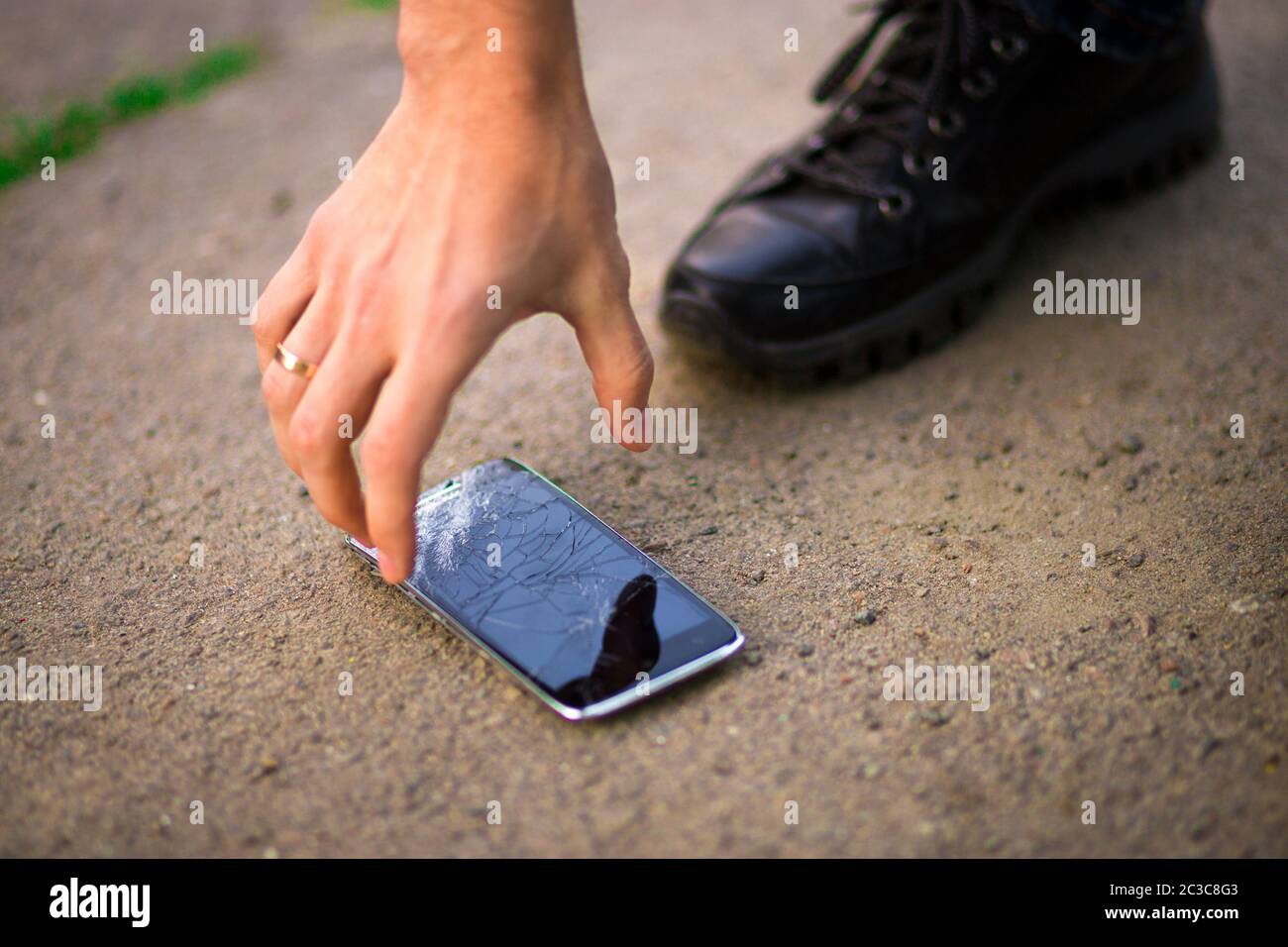 Persona che sceglie lo smartphone rotto schermo rotto a terra Foto Stock