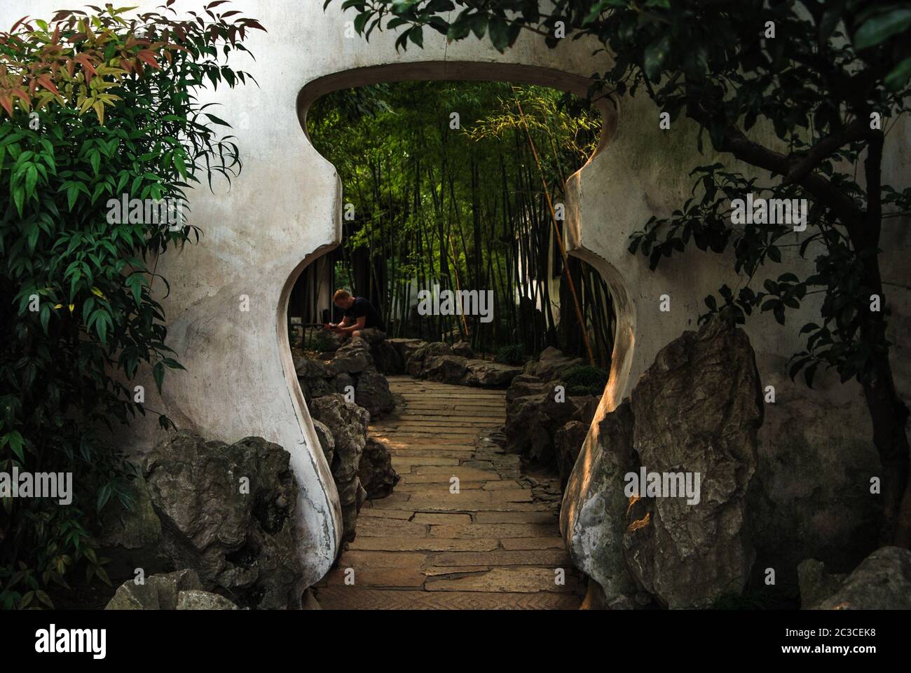 Una vista del cancello in stile cinese a forma di vaso nel giardino cinese con alberi di bambù e pietre a Pechino, Cina. Foto Stock