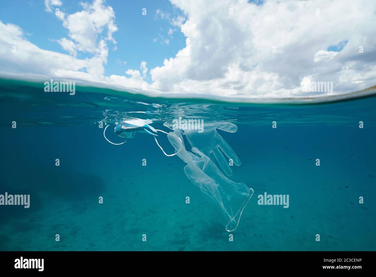 Inquinamento da rifiuti di plastica in mare dal coronavirus COVID-19 pandemico, maschera facciale con guanti subacquei e cielo con nuvola, vista divisa sopra sotto l'acqua Foto Stock