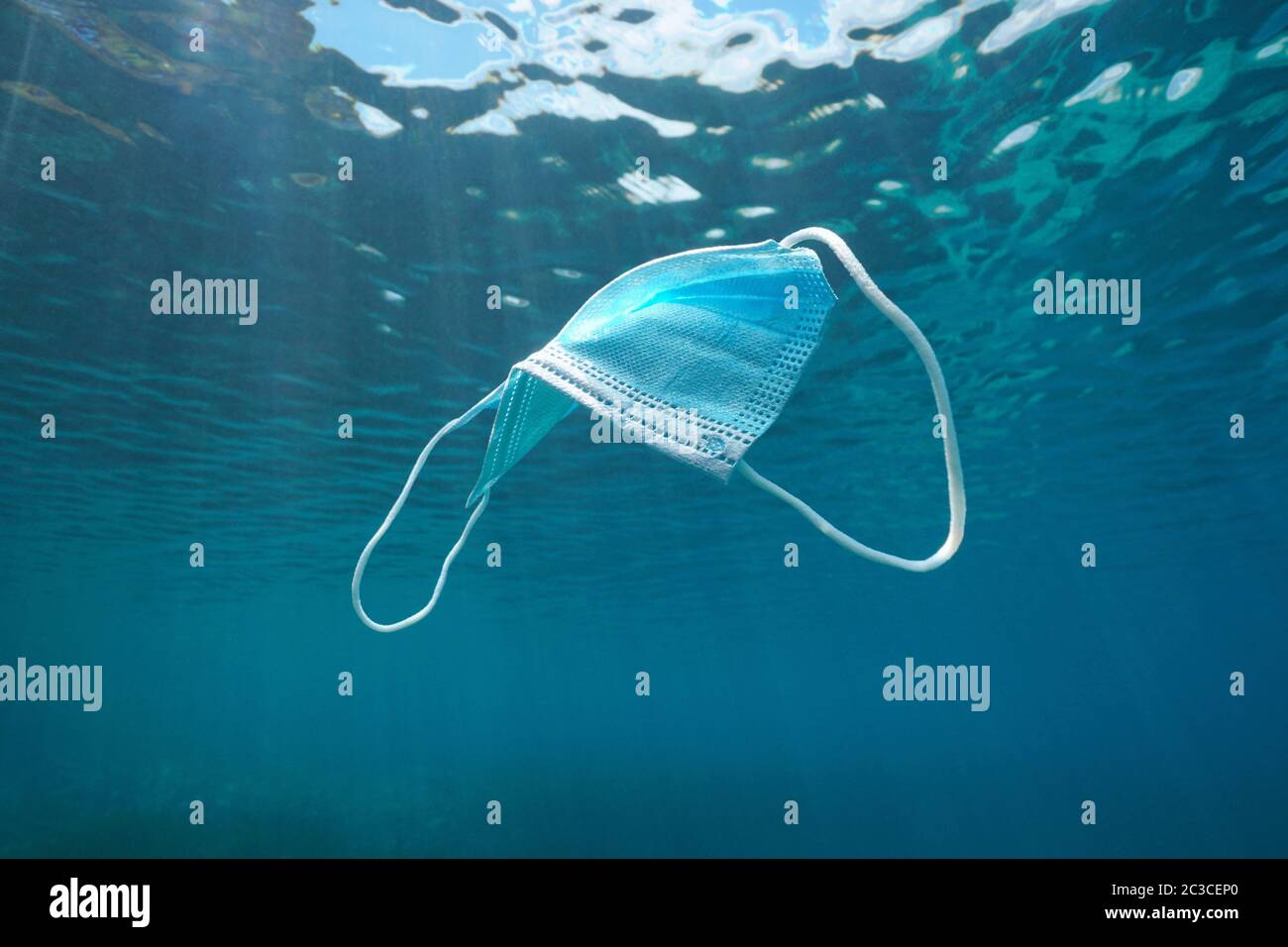 Maschera chirurgica monouso subacquea, rifiuti di plastica nell'oceano da coronavirus COVID-19 pandemia Foto Stock