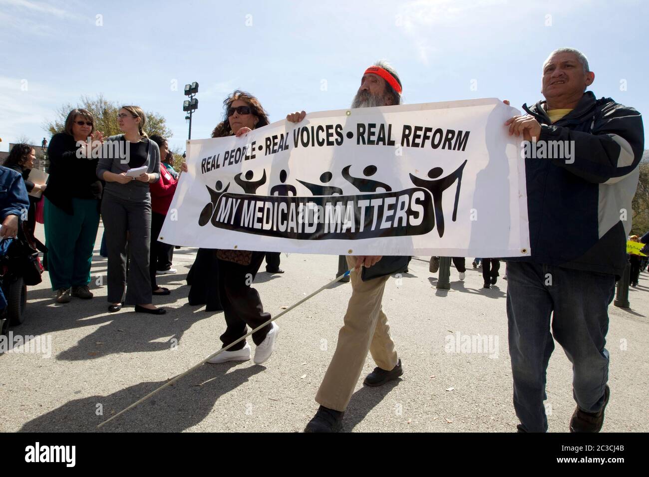 Austin, Texas USA, marzo 2013: Un uomo con problemi di vista, affiancato da manifestanti, partecipa a un rally di espansione pro-Medicaid al Texas Capitol di Austin, Texas Gov. Rick Perry ha recentemente annunciato la sua decisione che lo stato non accetterà alcun denaro federale per espandere il programma di assicurazione che copre principalmente a basso reddito e disabili Texans. Marzo 2013. ©Marjorie Kamys Cotera/Daemmrich Photography Foto Stock