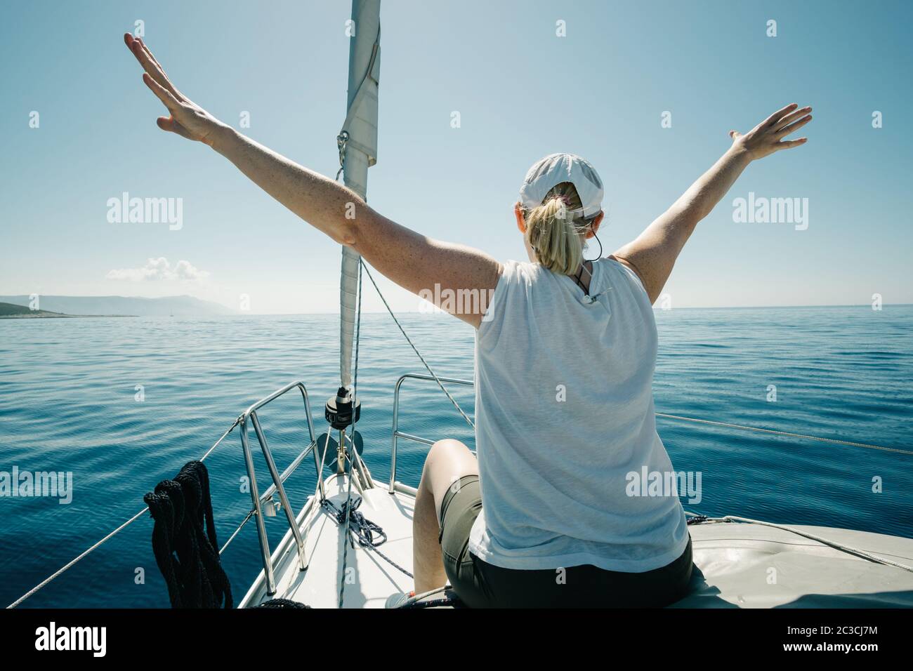 Donna seduta sulle navi prua godendo il viaggio yacht con le braccia aperte. Vela, vela e tr Foto Stock