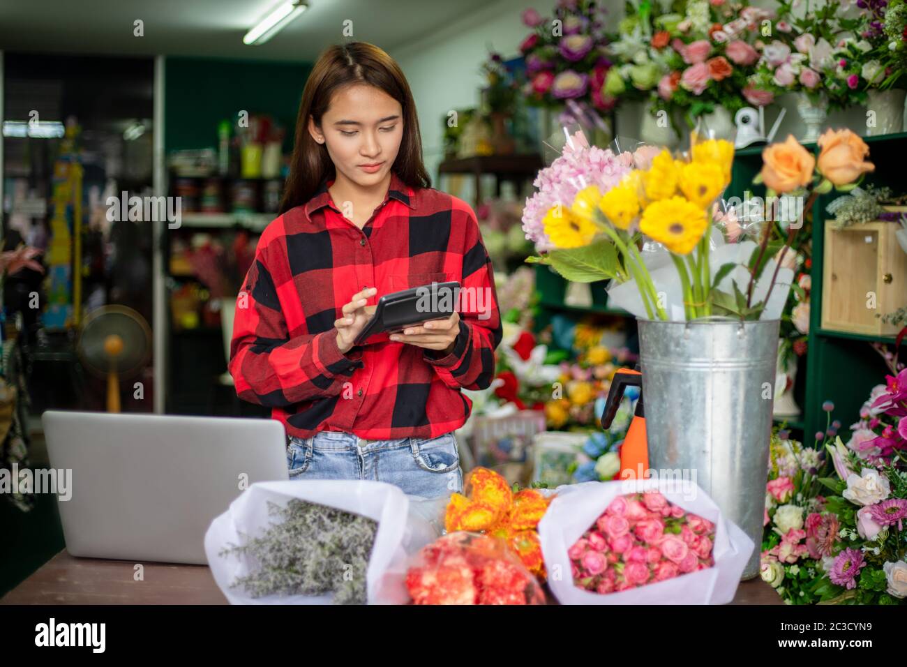 Asian Woman Florist piccolo Business Flower Shop Proprietario calcolatrice per lavorare per prendere ordini per il suo negozio. Foto Stock