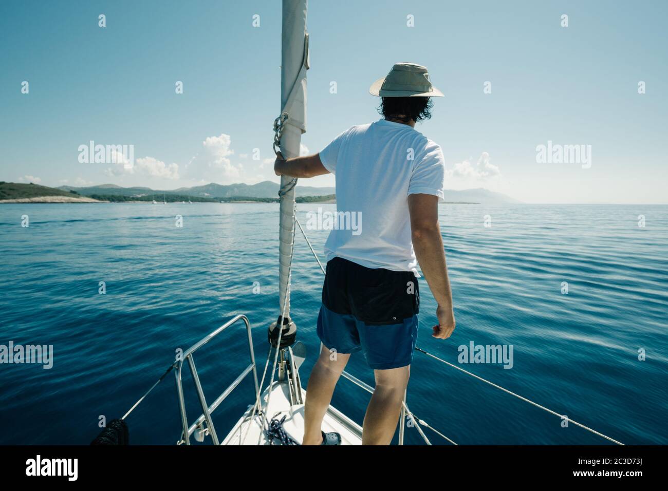 Uomo in piedi sulle navi si inchinano godendo il viaggio in yacht. Vela, vela e concetto di viaggio. Foto Stock