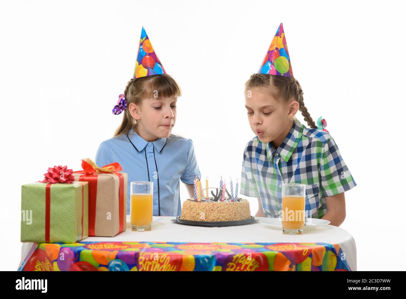 I bambini soffiano le candele su una torta di compleanno Foto Stock