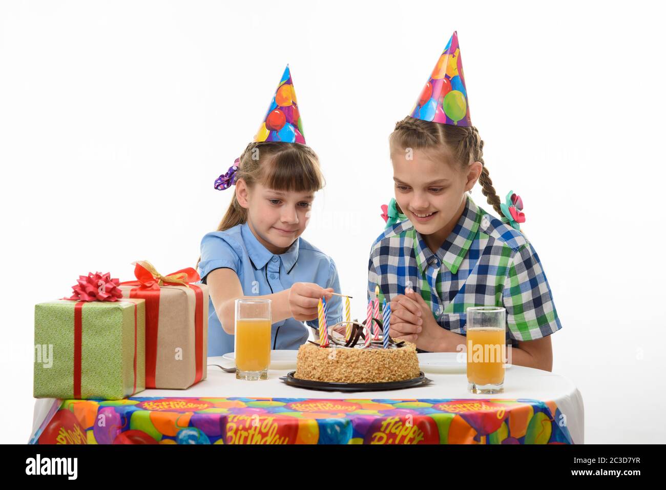 i bambini illuminano le candele con una partita sulla torta, al tavolo alla festa di compleanno Foto Stock