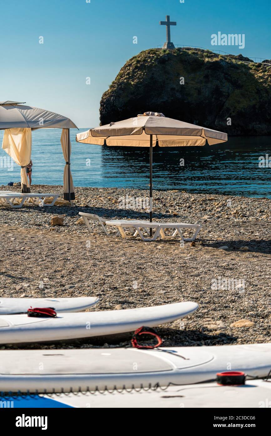 Tavole SUP in fila e tettoie sulla spiaggia all'alba, la mattina presto. Tende da spiaggia di lusso presso un lussuoso resort sulla spiaggia. Concetto di spiaggia estiva, relax e tra Foto Stock