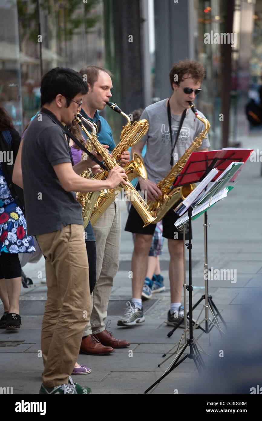 Quartetto di musicisti di strada su una strada cittadina. Quattro persone con strumenti a vento, tre sassofoni e un clarinetto giocano all'aria aperta. Aprile Foto Stock