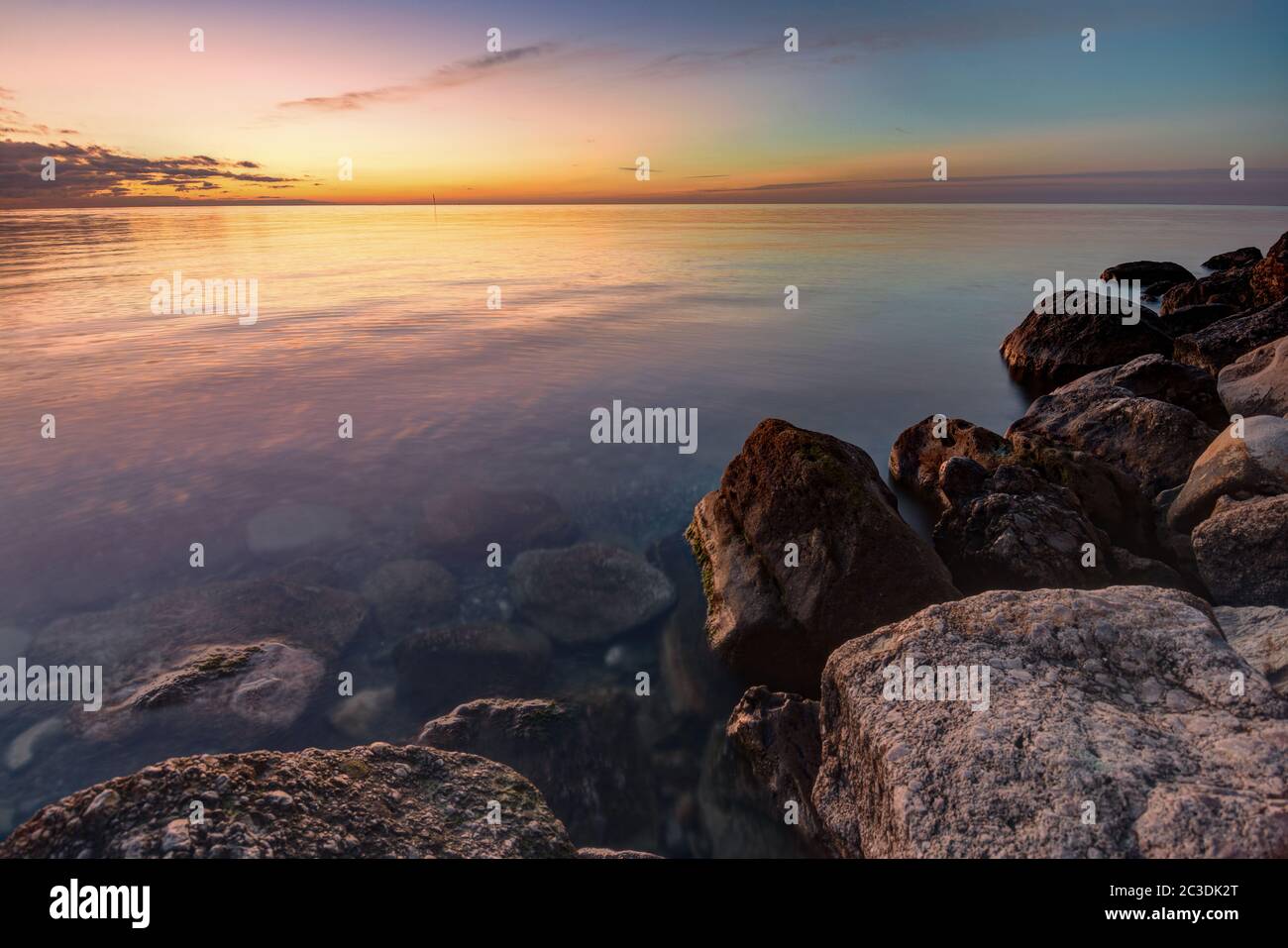 Calma bella serata di mare, in primo piano enormi pietre Foto Stock