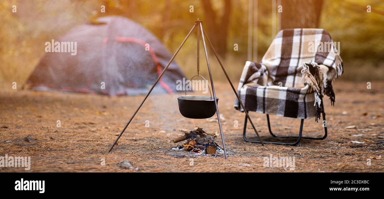 Relax e preparazione di cibo sul fuoco in campeggio, riposo autunno all'aperto nella foresta Foto Stock