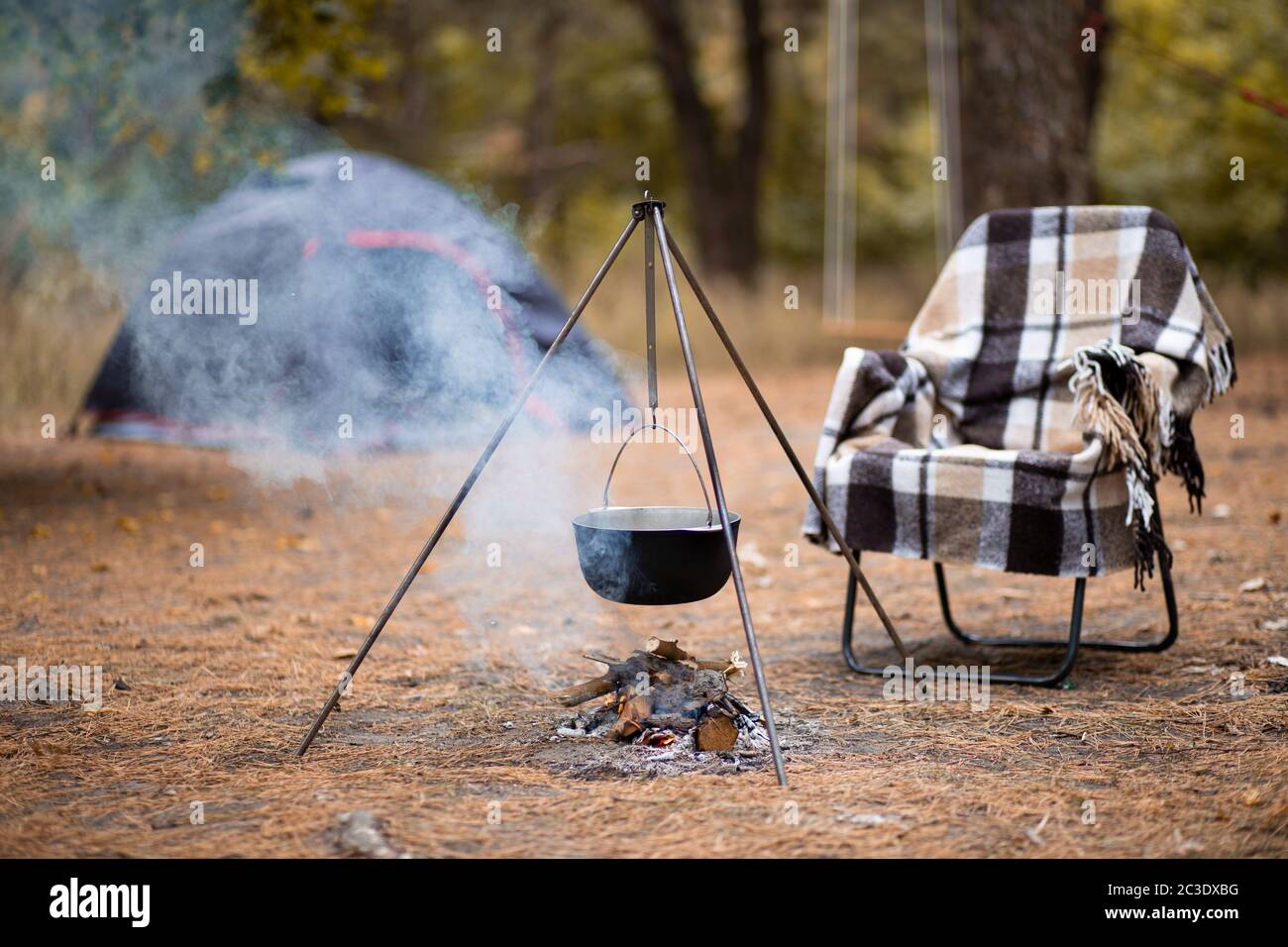 Relax e preparazione di cibo sul fuoco in campeggio, riposo autunno all'aperto nella foresta Foto Stock