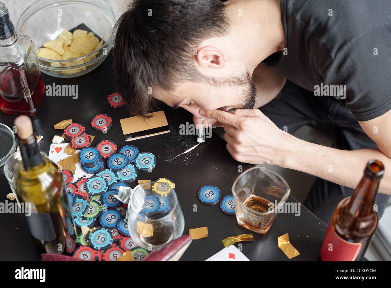 Giovane uomo russare droga polvere attraverso il rotolo del dollaro mentre prendendo le droghe a partito Foto Stock