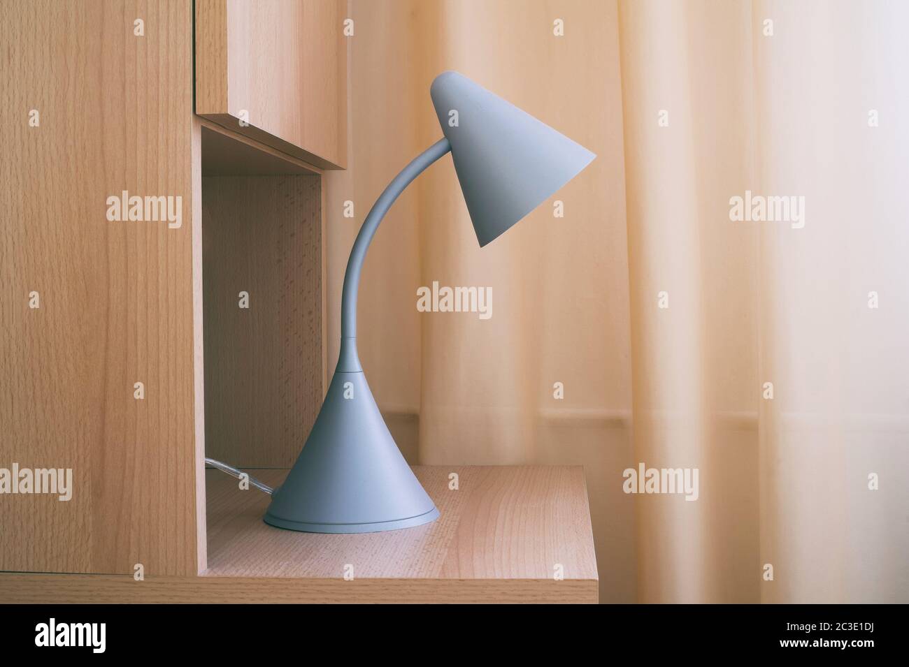 Particolare di camera da letto accogliente - lampada da lettura su comodino in legno. Tenda unicolor sullo sfondo. Design semplice e moderno Foto Stock