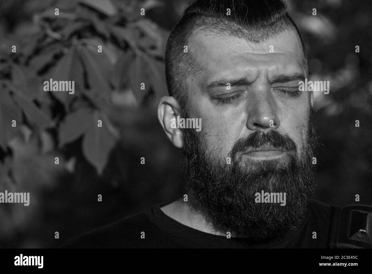 Uomo con barba al tramonto. Grande ritratto facciale di un uomo bearded di 40 anni. Verticale a faccia intera. Uomo in una T-shirt nera Foto Stock