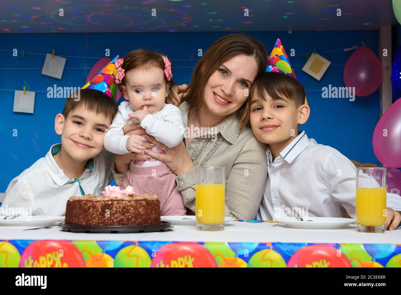 Mamma, due figli e una bambina al tavolo delle feste all'interno della casa Foto Stock