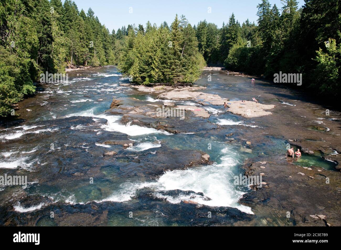 Persone che nuotano in piscine di roccia in un luogo chiamato Medicine Bowls sul fiume Browns vicino a Courtenay, Vancouver Island, British Columbia, Canada. Foto Stock
