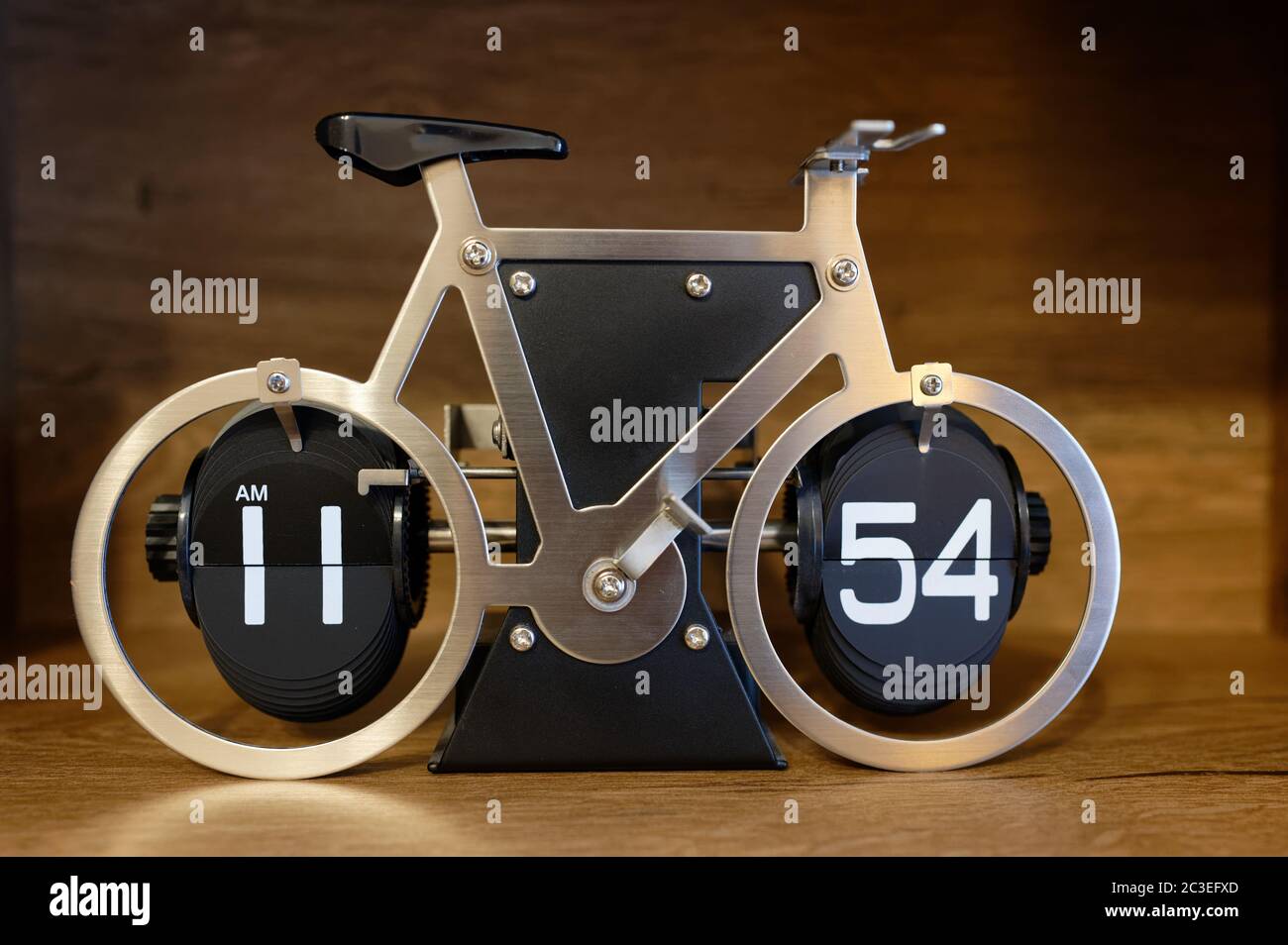 Orologio da tavolo originale che mostra il tempo, che sembra una bicicletta in metallo e plastica in piedi su una mensola di legno Foto Stock