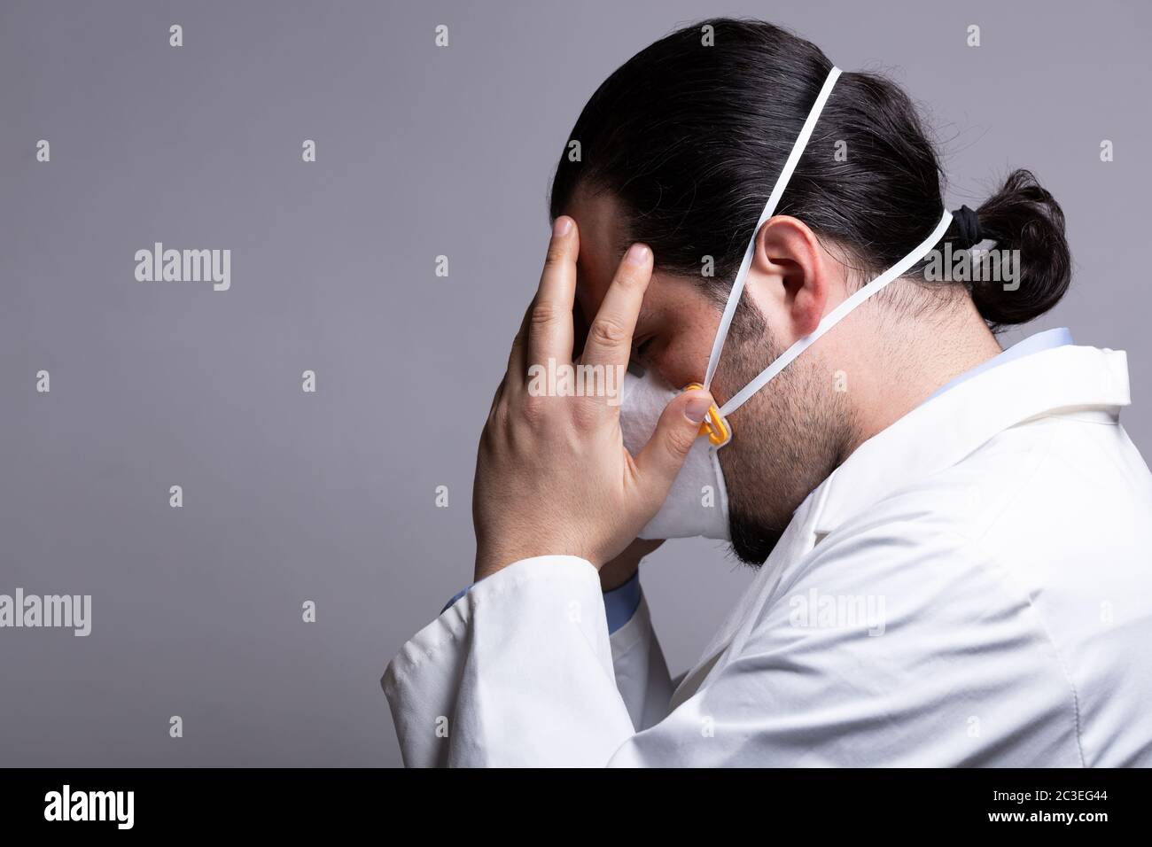 Medico frustrato che indossa una maschera respiratoria che tocca la testa con le mani. Burnout e. Foto Stock