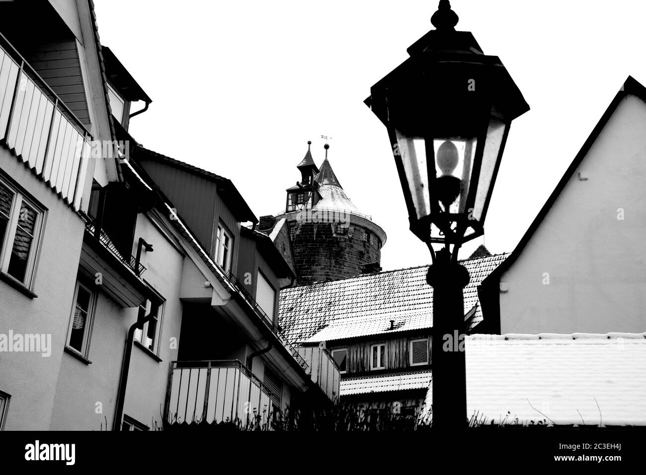 Città vecchia con tetti innevati e torre di guardia medievale in bianco e nero Foto Stock