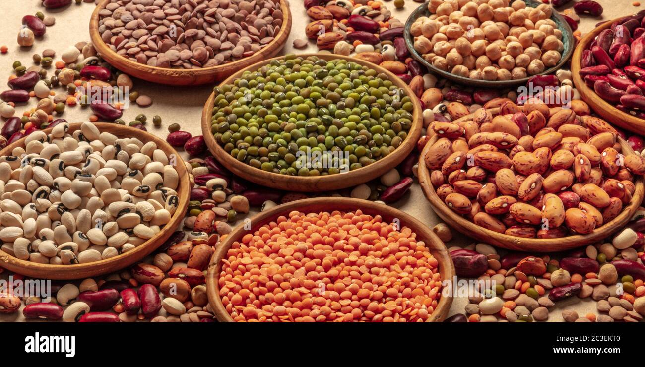 Assortimento di legumi su sfondo marrone. Lenticchie, soia, ceci, fagioli rossi, una ventata di impulsi Foto Stock