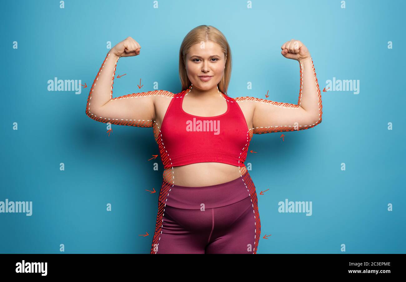 Determinata ragazza vuole rimuovere grasso e fa palestra a casa. Espressione soddisfatta. Sfondo ciano Foto Stock