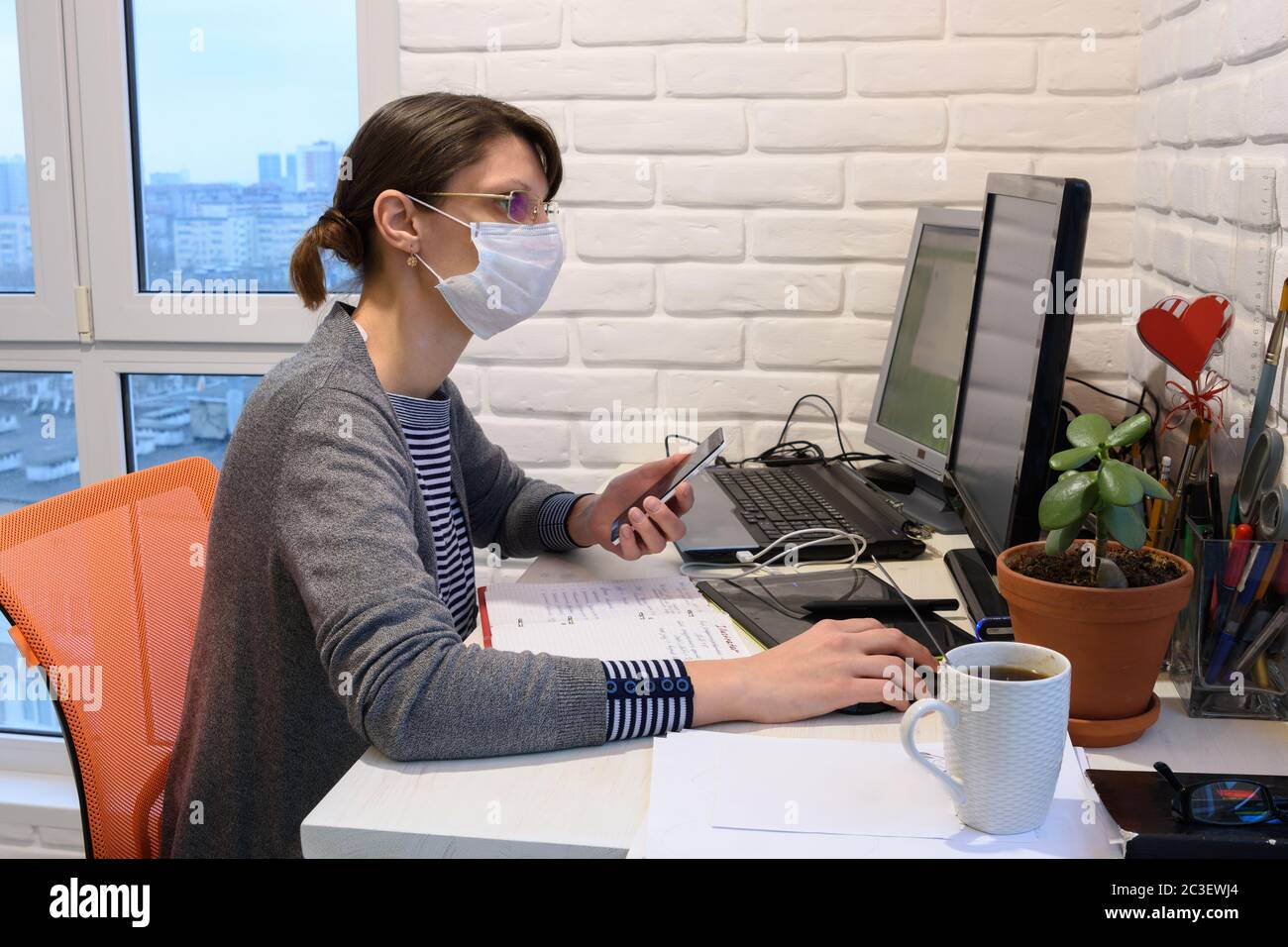 Una ragazza malata in una maschera medica in auto-isolamento funziona a distanza Foto Stock