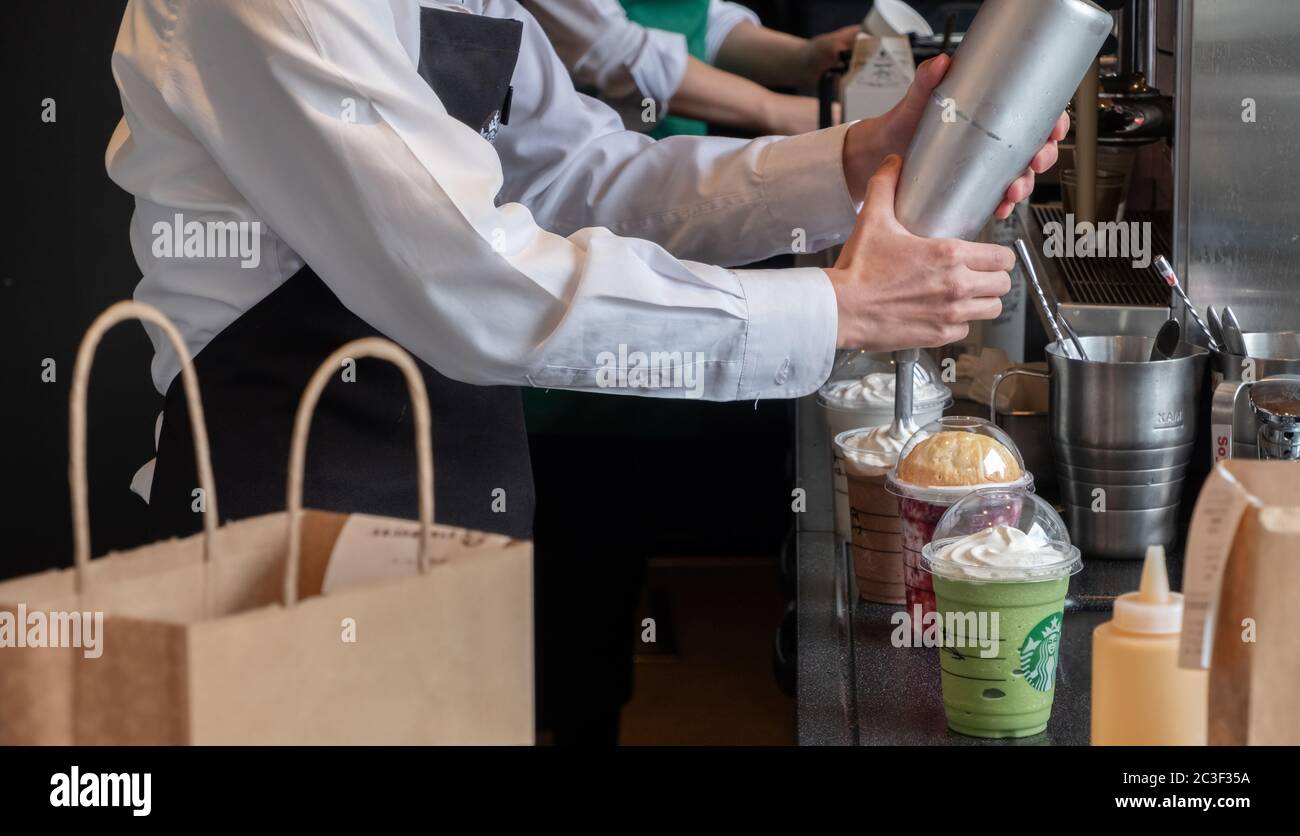 Il barista che fa i clienti ha fatto la loro bevanda presso la caffetteria Starbucks, la stazione di Nakameguro, Tokyo, Giappone Foto Stock