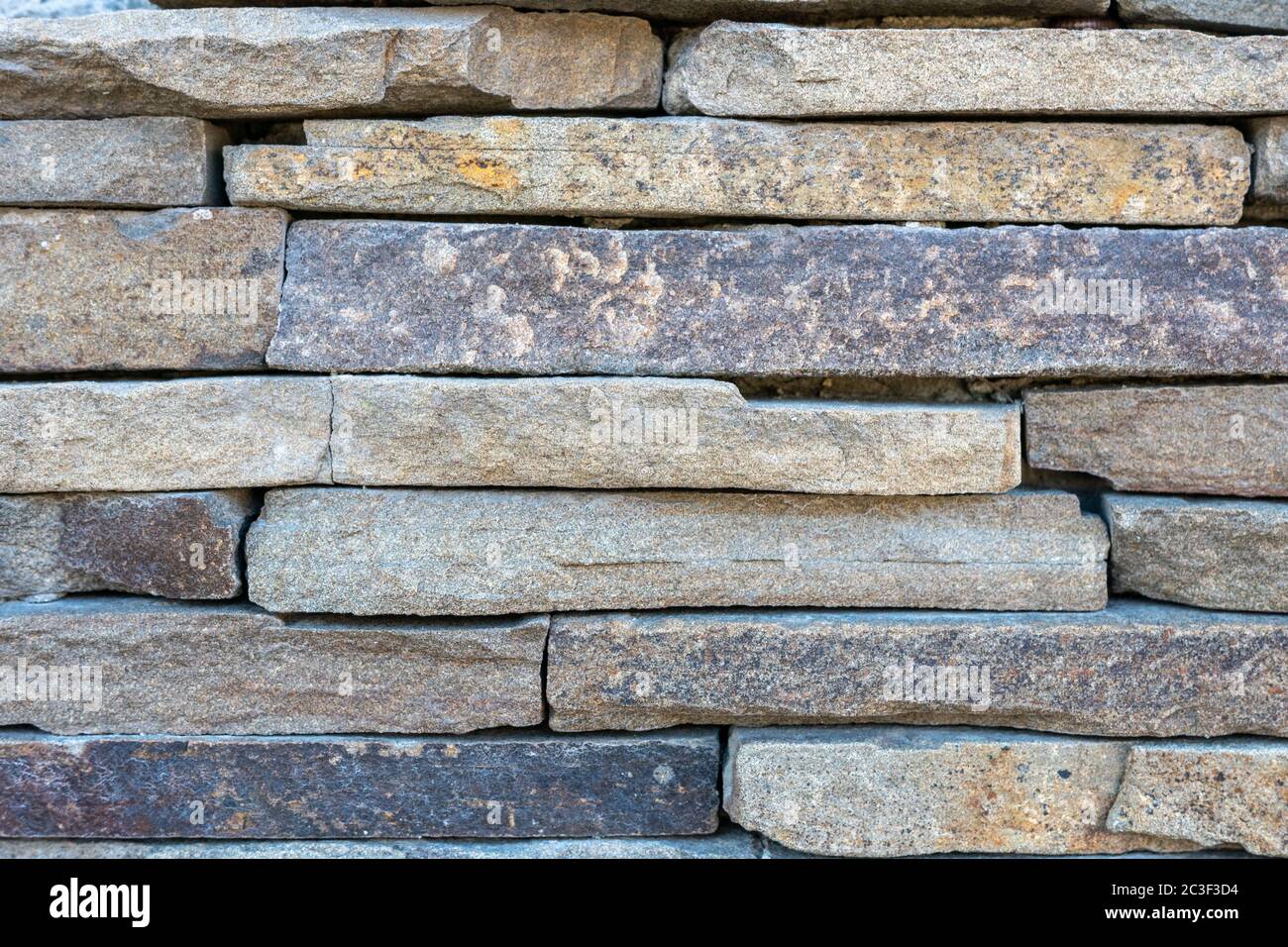 Struttura del muro di pietra arenaria grigia. Superficie irregolare della parete di arenaria. Decorazione di pareti esterne con mattoni di pietra arenaria selvatica. Foto Stock