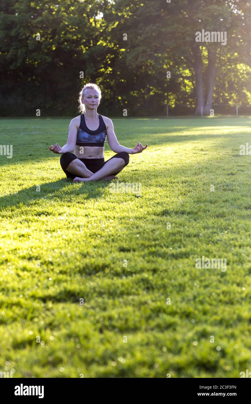 Donna (38) che pratica yoga su un prato nel parco, Kiel, Schleswig-Holstein, Germania Foto Stock