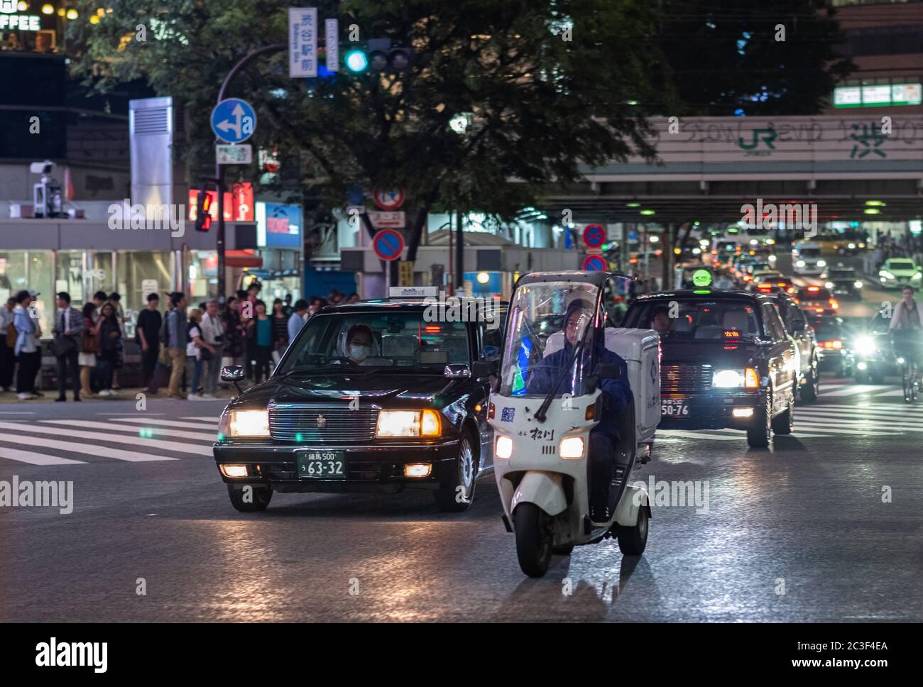 Uomo che cavalcano in bici coperta nella strada di Shibuya di notte, Tokyo, Giappone Foto Stock