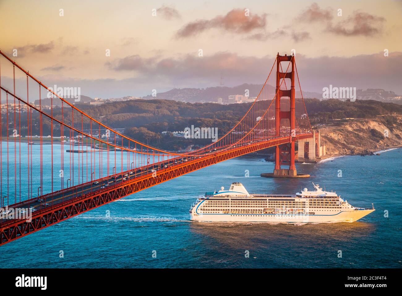 Vista panoramica della nave da crociera passando dal famoso Golden Gate Bridge con lo skyline di San Francisco sullo sfondo al tramonto, California, USA Foto Stock