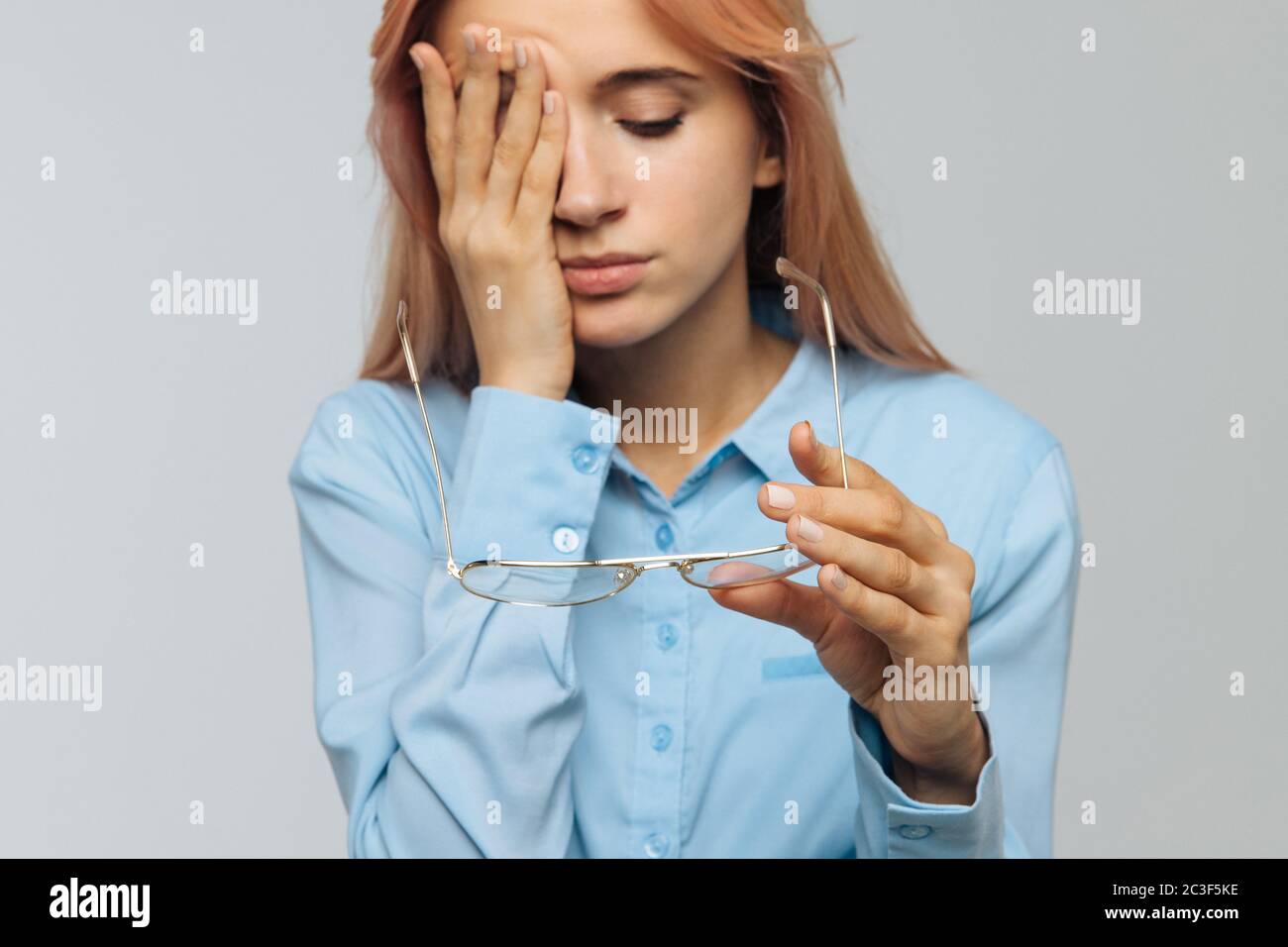 Ritratto di giovane donna caucasica con occhiali che tengono in mano sfregando gli occhi, si sente stanco dopo aver lavorato sul computer portatile, concentrarsi sugli occhiali. Lavori in eccesso, pneumatico Foto Stock