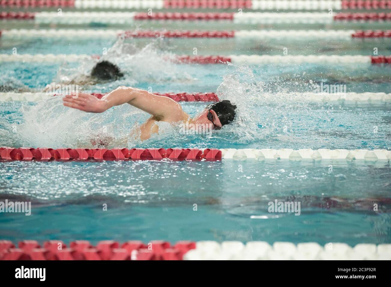 Un giovane nuotatore maschile di scuola superiore nuota freestyle durante un incontro di nuoto Foto Stock