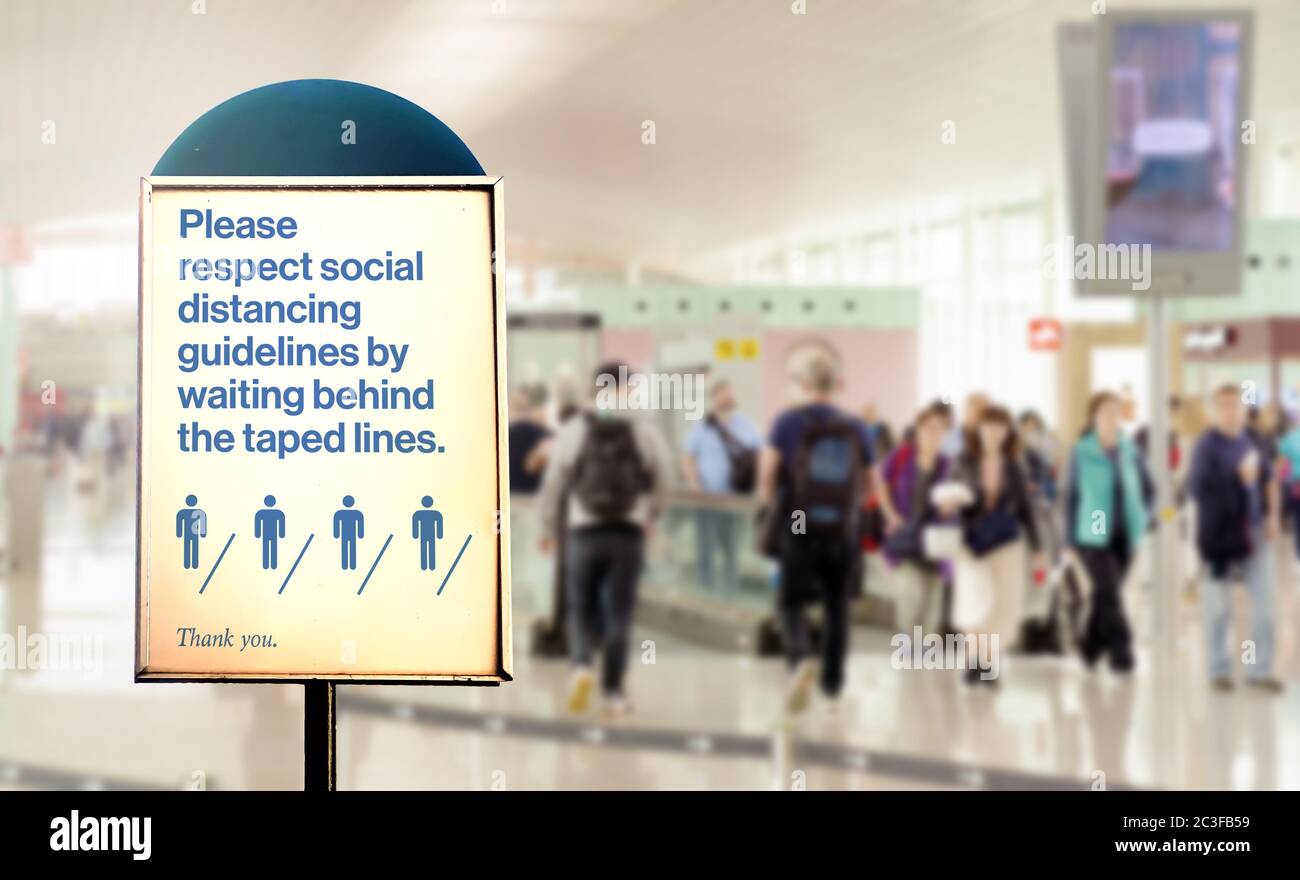 un cartello all'interno di un aeroporto avverte della necessità di mantenere la distanza minima di sicurezza tra le persone Foto Stock