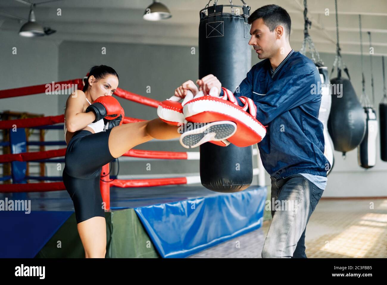 Pugile femminile kick boxing mitts tenuto da personal trainer presso palestra fitness Foto Stock