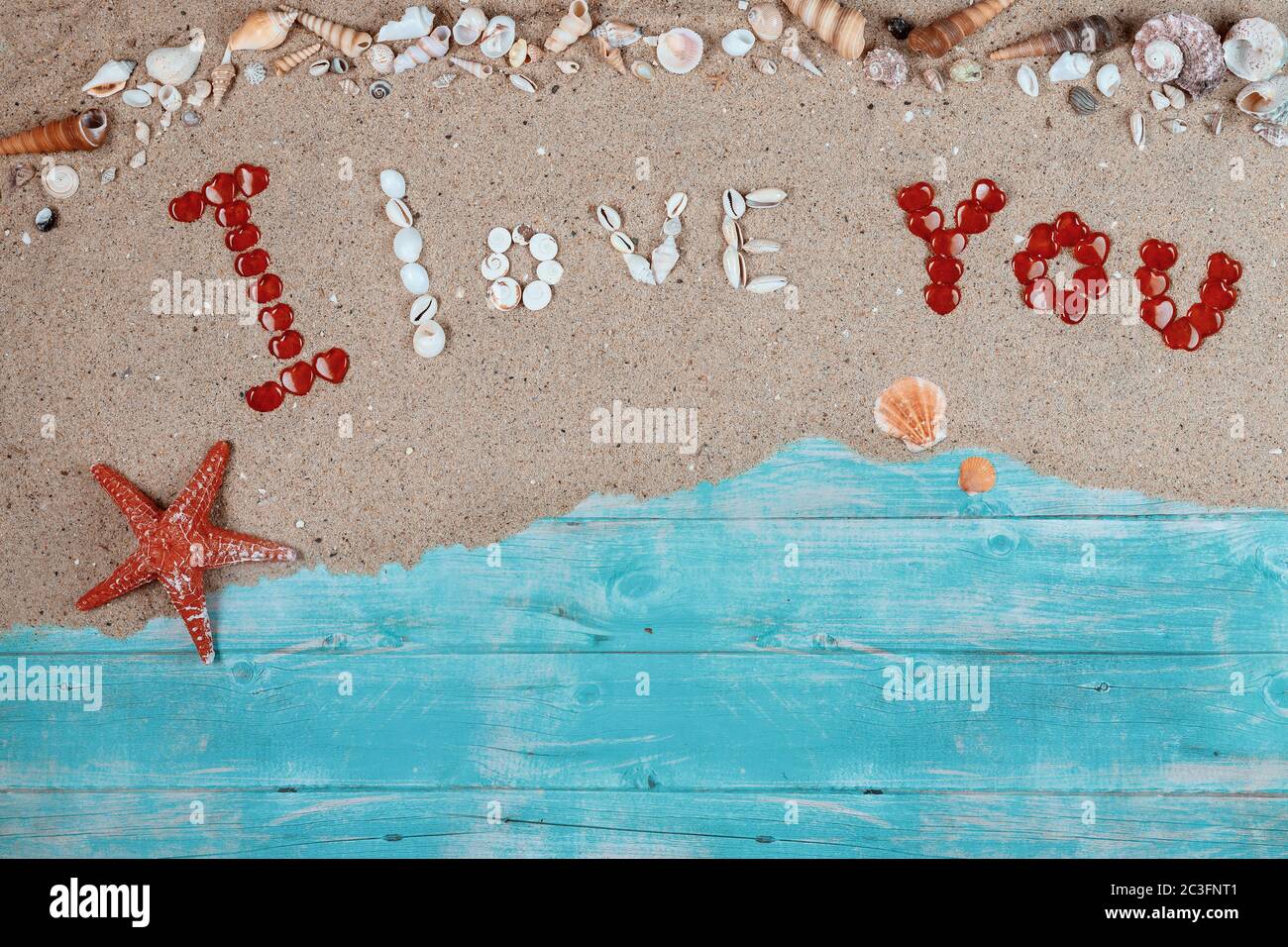 Ti amo tasse sulla sabbia dell'oceano con stelle marine rosse. Concetto di giorno di San Valentino. Foto Stock