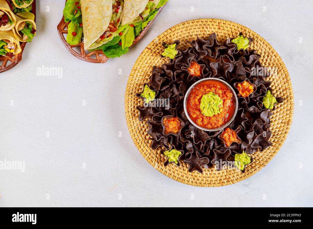 Tortilla di mais blu con salsa e guacamole su sfondo bianco. Cibo ispanico. Foto Stock