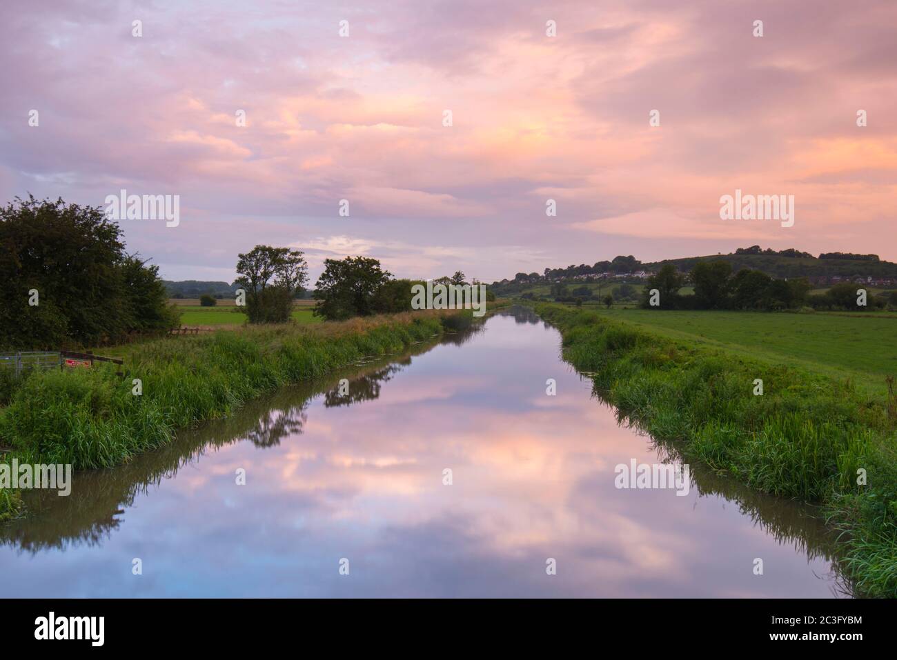 Glastonbury, Somerset, Regno Unito. 20 giugno 2020. Regno Unito Meteo. Le nuvole ad ovest illuminano rosa e si riflettono nel fiume Blue a Glastonbury nel Somerset durante l'alba del solstizio estivo. Immagine: Graham Hunt/Alamy Live News Foto Stock