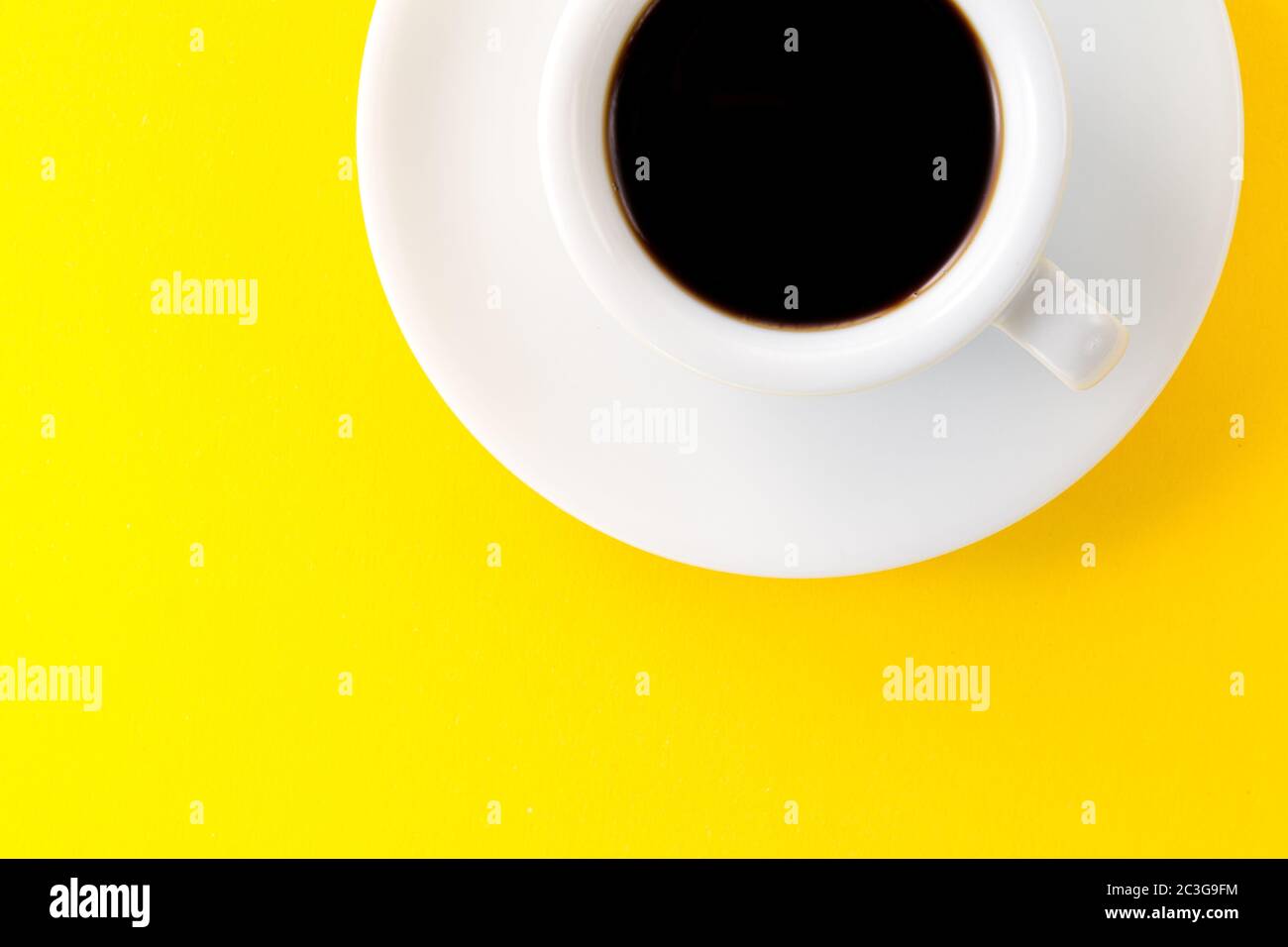 Caffè espresso in piccola tazza bianca in ceramica su sfondo giallo vibrante. Minimalismo alimentare mattina energia concetto. Foto Stock