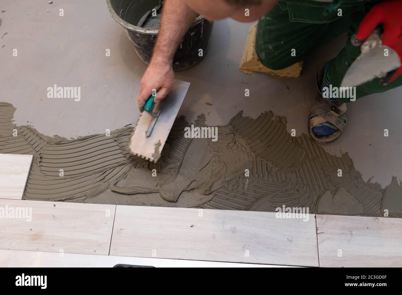 Operaio di costruzione professionale che posa piastrelle in ceramica sul pavimento nella stanza da bagno. Foto Stock