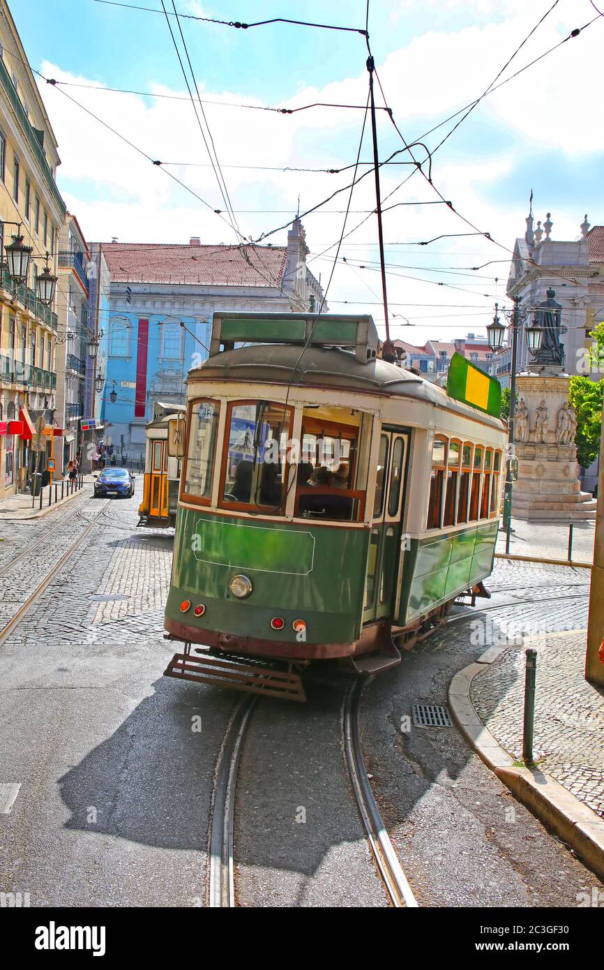 Tram verde storico contro le strade della città vecchia, parte della rete tramviaria dal 1873, Lisbona, capitale del Portogallo. Foto Stock