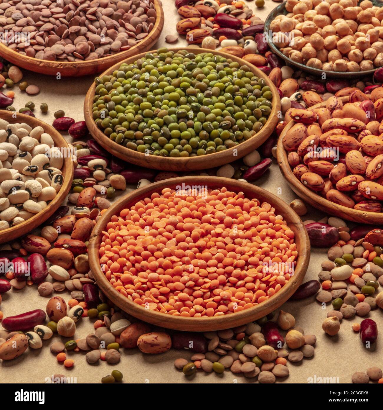 Assortimento di legumi su sfondo marrone. Lenticchie, soia, ceci, fagioli rossi, una ventietà di impulsi, colpo quadrato Foto Stock