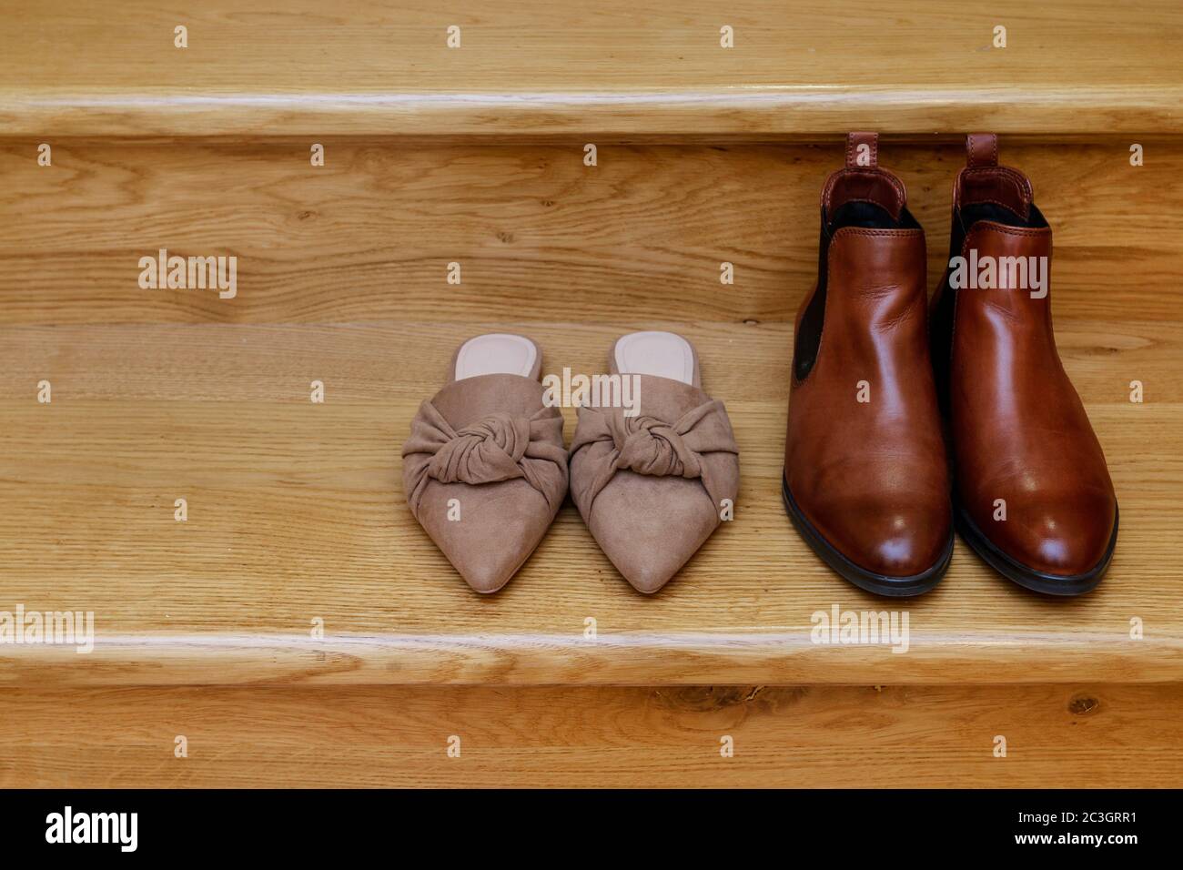 Un paio di scarpe mule e stivali Chelsea sulle scale. Immagine concettuale delle scarpe di donna e uomo insieme. Foto Stock