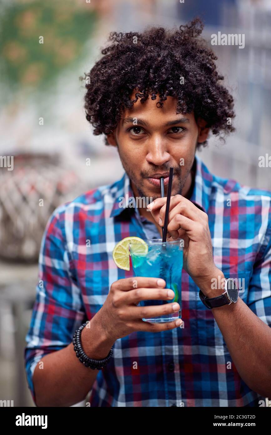 Ritratto fotografico di giovane ricciolo ispanico con cocktail Foto Stock