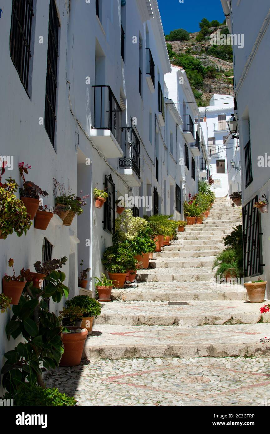 Una vista su un vicolo stretto e ripido nella graziosa cittadina bianca di Frigiliana, in Andalusia, Spagna meridionale. Paesaggio pittoresco con bellissima Foto Stock