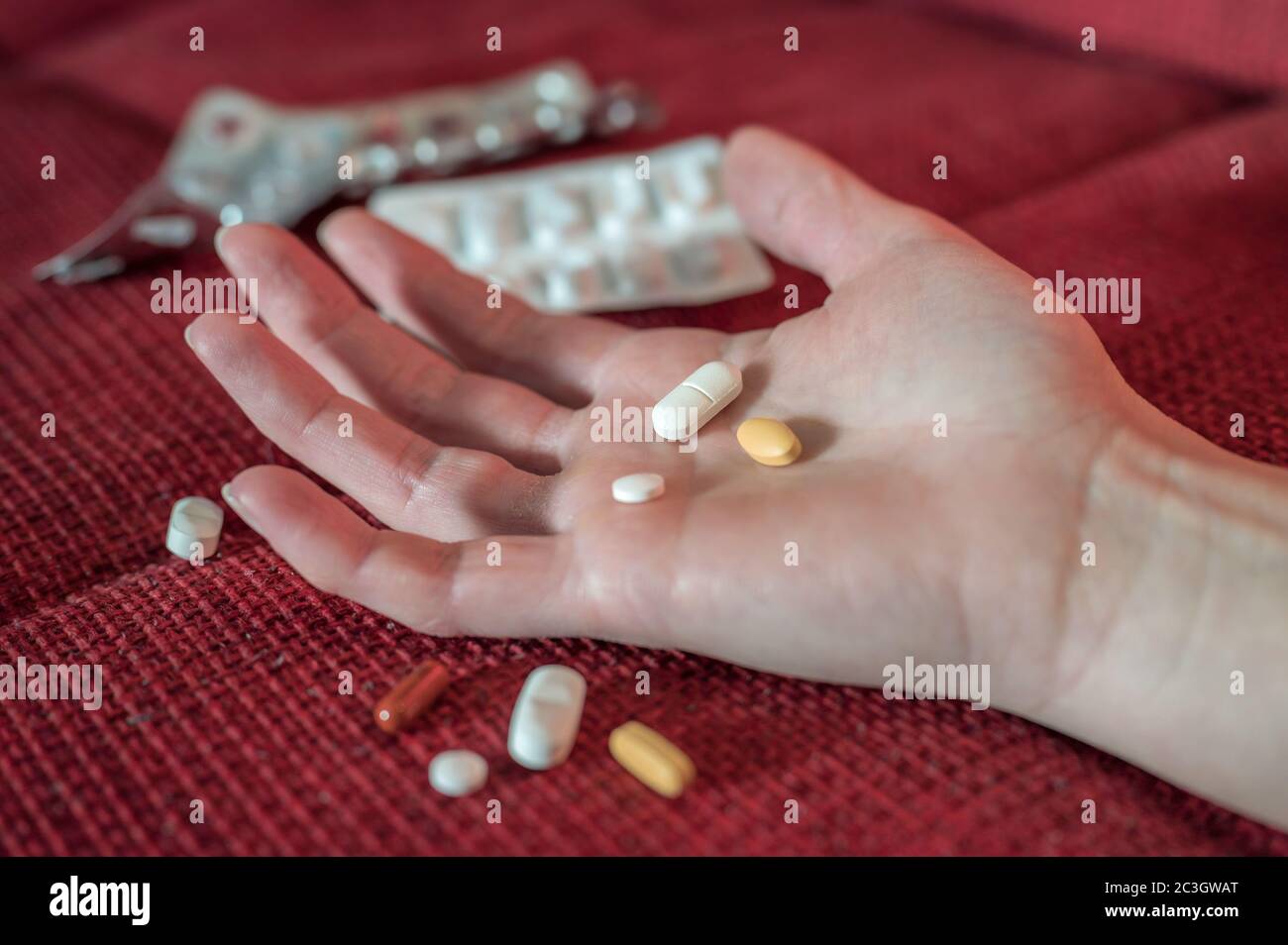 Un pericoloso sovradosaggio di droga simbolizzato con la mano di una donna e le compresse Foto Stock