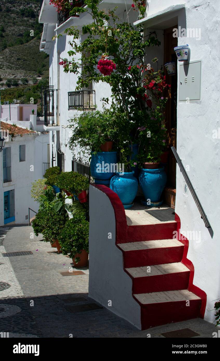 Una vista su una stradina nella graziosa cittadina bianca di Frigiliana, in Andalusia, Spagna meridionale. Una pittoresca strada stretta e tortuosa. Foto Stock