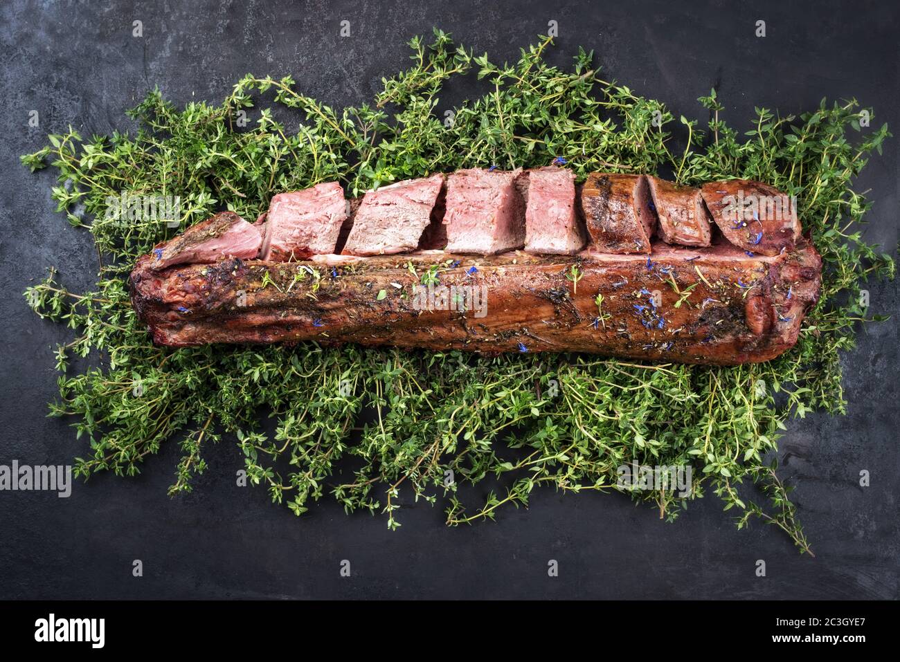 Filetto di cervo stagionato al barbecue e sella naturale con erbe offerte come vista dall'alto su un pannello rustico Foto Stock